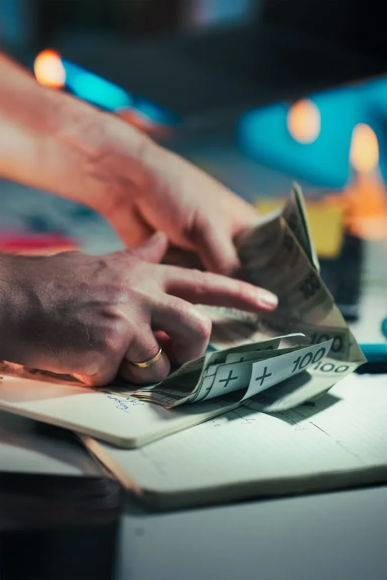 Două persoane discută prețul unei tranzacții, cu bancnote și calculator pe masă