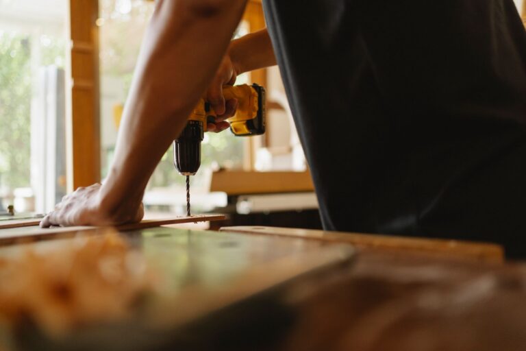 Cum alegi un meșter din anunțuri pentru reparațiile din casă Meșter care repară instalația de sub chiuveta unei bucătării, cu trusa de scule alături